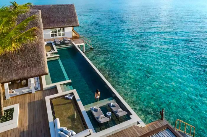 A woman enjoying a private plunge pool connected to an overwater bungalow at Four Seasons Maldives