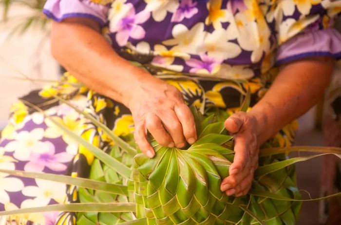 A woman crafting a hat from palm leaves