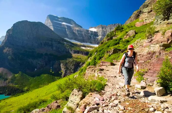 A woman in her early thirties navigates the Grinnell Glacier trail in Glacier National Park, Montana. This trail is a favorite among visitors as it leads directly to one of the few remaining glaciers in the park, a poignant reminder of climate change.