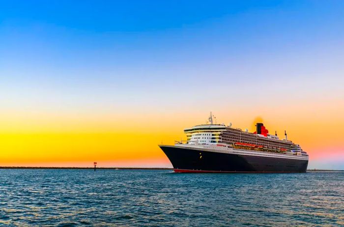 A Cunard cruise ship gracefully sails into the sunset.