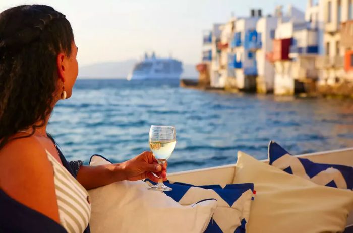 A woman savoring a glass of wine aboard a Silversea ship along the Greek coast