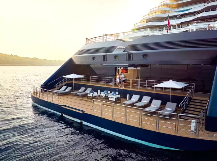 A couple enjoys the view from a balcony aboard the Evrima, a luxurious Ritz-Carlton yacht.