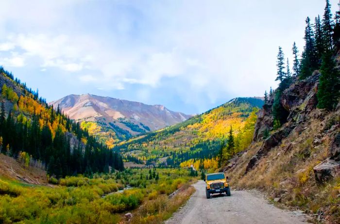 A yellow jeep traversing Cinnamon Pass during autumn in Colorado.