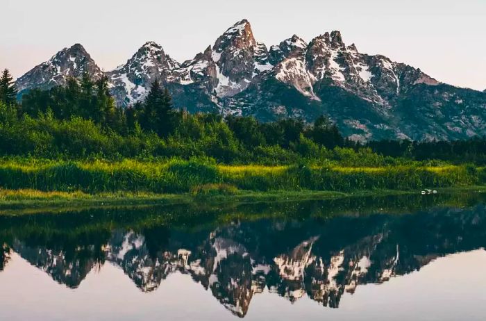 Mountains capped with snow next to a springtime lake