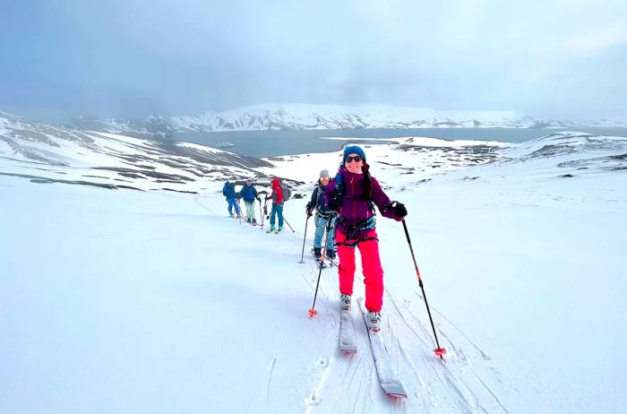 A woman guides a group skiing on Deception Island in Antarctica.