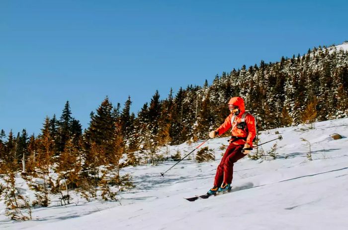 A woman in red skis down Baldface Mountain, NH, on a chilly morning.