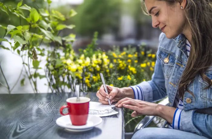 Amsterdam, Netherlands: A woman writing postcards at a café