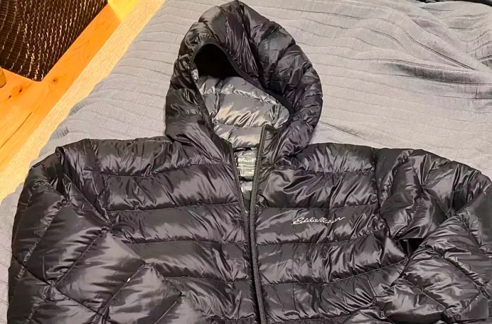 The Eddie Bauer Men's CirrusLite Down Hooded Jacket resting on a couch