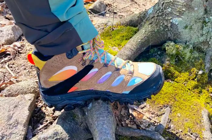 Individual standing on a tree root while wearing Merrell Moab 3 GTX Mid Hiking Boots