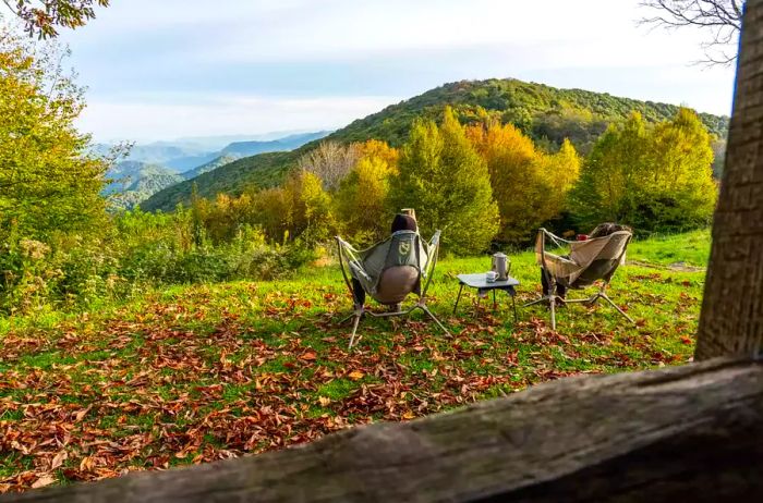 Two individuals seated in camping chairs, gazing at the scenery