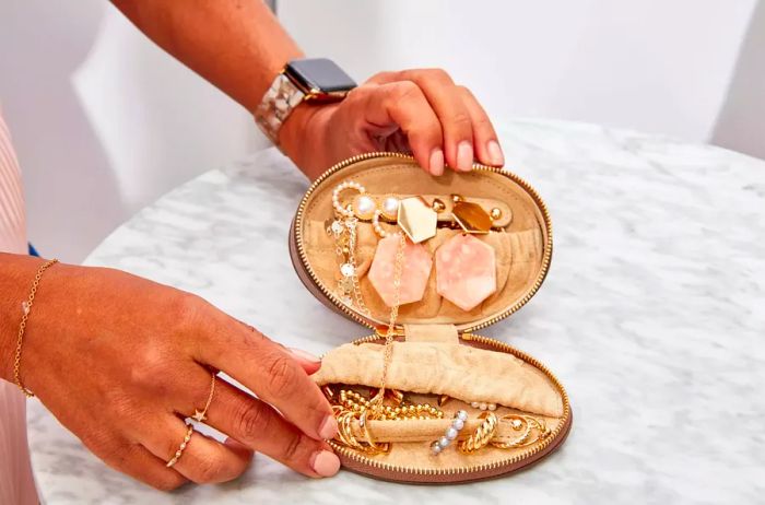 Hands displaying an open Cuyana Travel Jewelry Case