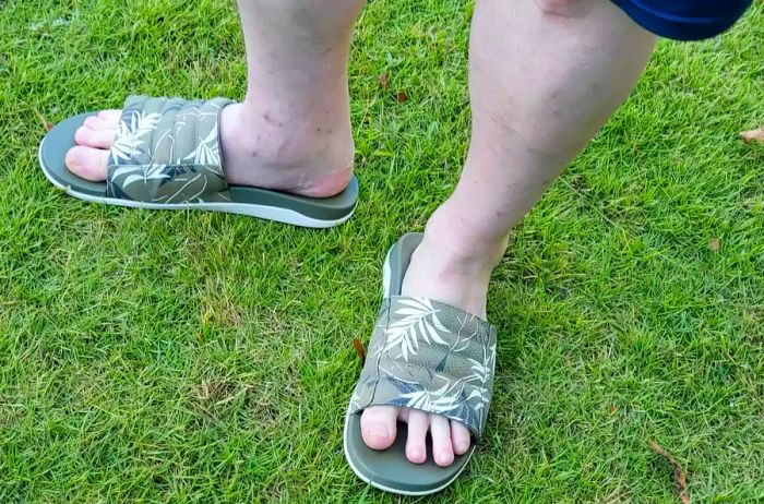 A person is seen wearing the OluKai MahaOlu Men's Slide Sandals