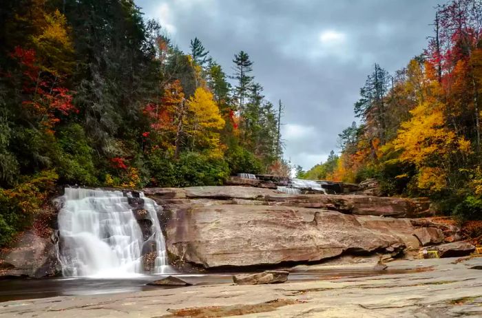 Triple Falls cascading through a vibrant autumn forest in the Appalachian Mountains of North Carolina