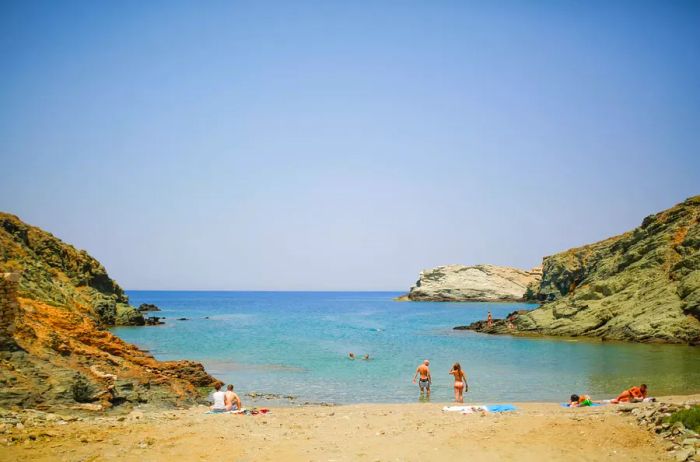 Visitors unwind on the beach under the midday sun in Folegandros, Greece