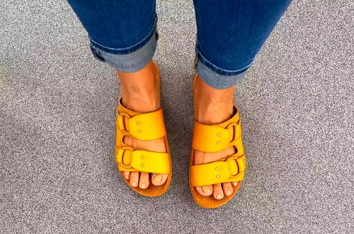 A person showcases the Reef Cushion Vera Cruz Slide outdoors.