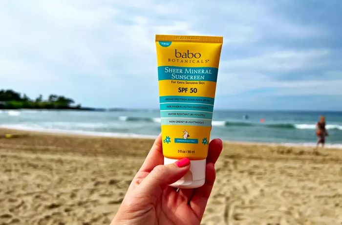 Close-up of a hand holding Babo Botanicals Sheer Mineral Sunscreen Lotion SPF 50