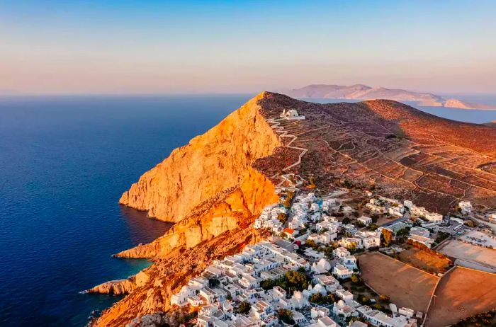 Greece, Cyclades Islands, Folegandros Island, Chora, the island's capital, perched on a cliff overlooking the sea with the church of Panagia Kimissis nearby.