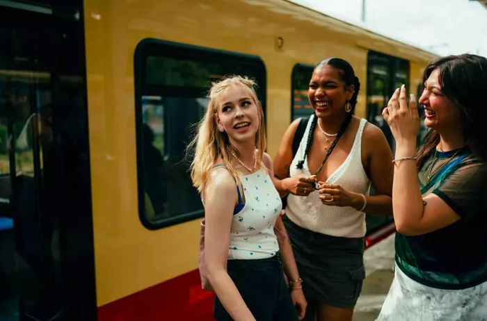 Three Gen Z friends await the train during their travels.