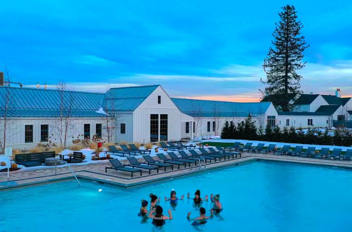 Groups of people gather in an outdoor pool during winter