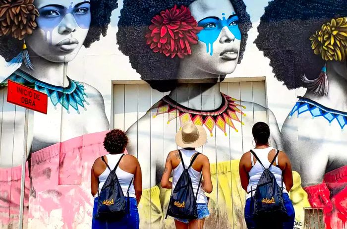 Three women admiring vibrant street art in Cartagena, Colombia