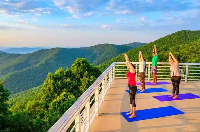 A group practicing yoga on a rooftop with a mountain view