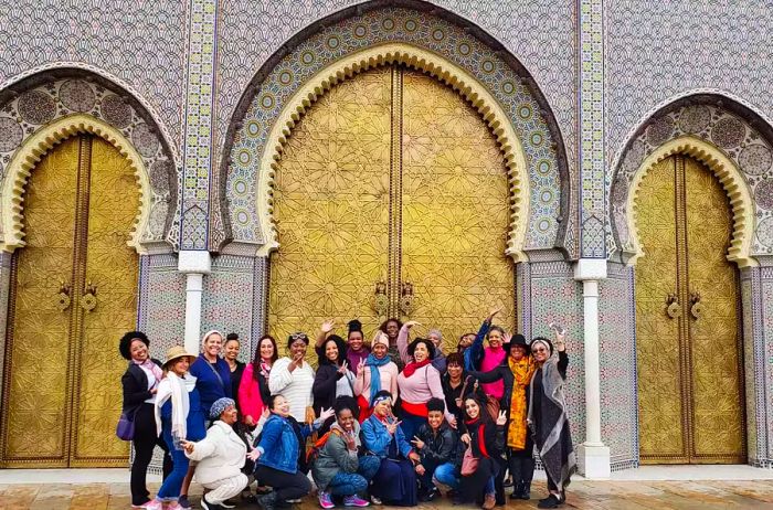 A group of women posed in front of a beautifully tiled facade in Fez, Morocco