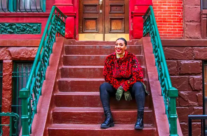 Evita Robinson perched on the steps of a townhouse in Harlem, New York.