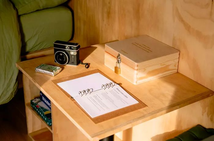 A lockbox, camera, and guidebook resting on a wooden countertop