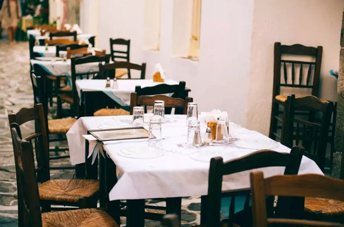 Milos, Greece. A restaurant with vacant tables along a street in Plaka