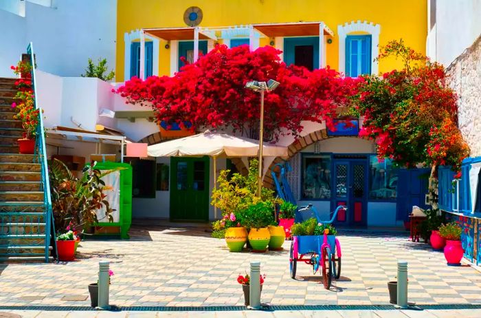 A charming street adorned with vibrant houses and blooming bougainvillea flowers in Adamantas town on Milos island, Greece