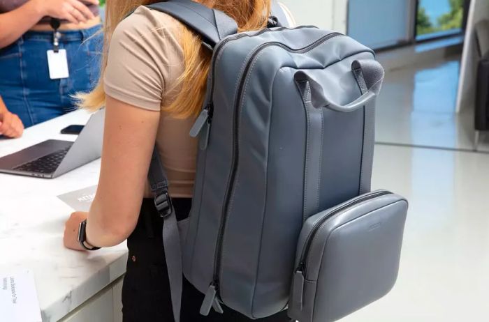 Individual showcasing the Monos Metro Backpack while standing at the counter