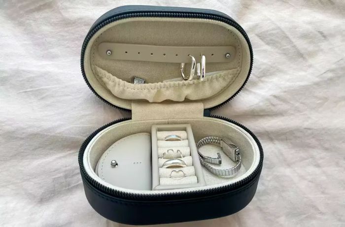 Monos Travel Jewelry Case open and displayed on a bed