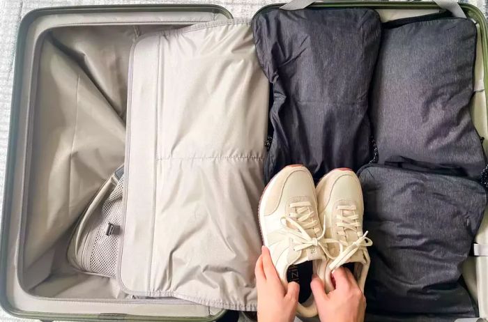 A person loading sneakers into the Monos Check-in Medium