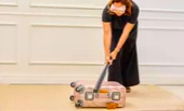 An individual striking the TUMI 19 Degree Aluminum International Carry-on with a bat