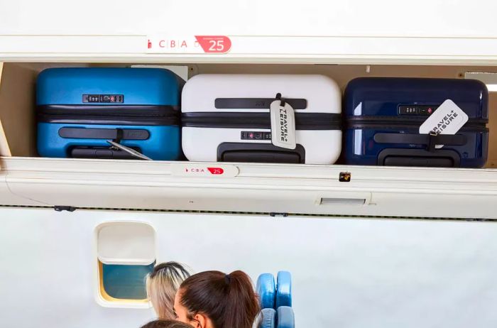 The carry-on from the Away Luggage Set nestled in an overhead compartment alongside other bags