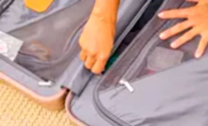 Close-up of someone zipping up the interior of the TUMI 19 Degree Aluminum International Carry-on