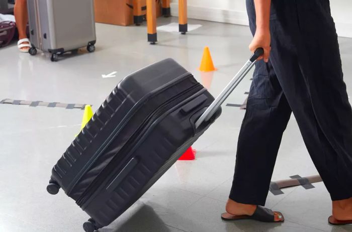 Individual pulling the Amazon Basics 20-inch Hardside Spinner across a tile floor