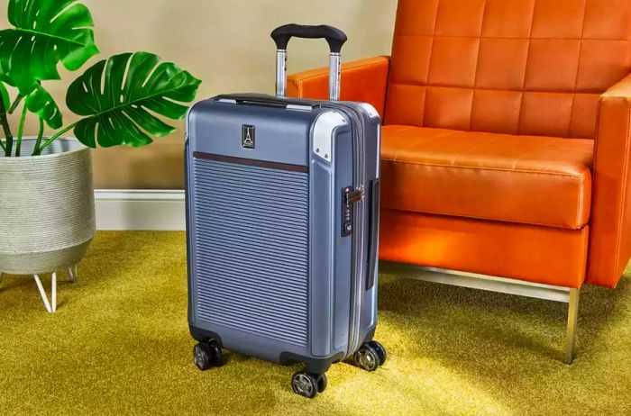 Travelpro Platinum Elite Carry-on Expandable Hardside Spinner showcased beside a leather chair