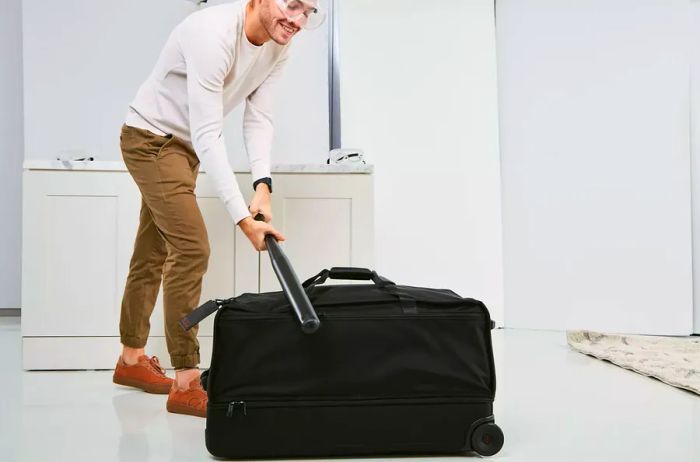 A person strikes the Tumi Alpha 3 Large Split 2-Wheeled Duffel with a baseball bat