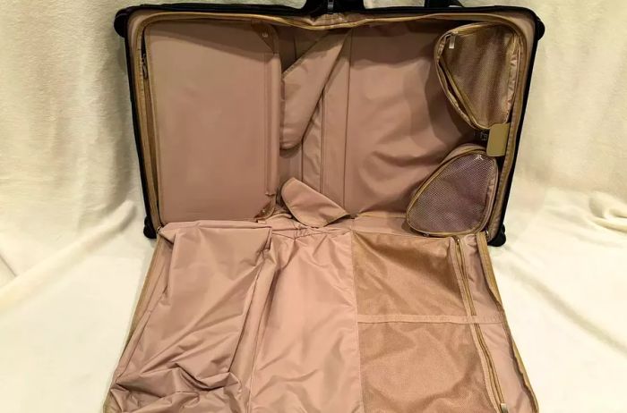 An empty Briggs & Riley Baseline 21-inch Carry-on Wheeled Garment Spinner against a cream-colored backdrop