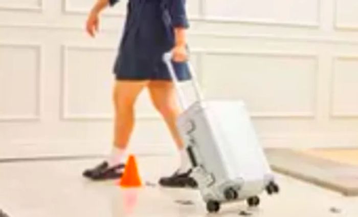 A person pushes the Zero Halliburton Classic Aluminum 3.0 International Carry-on 33L across the floor