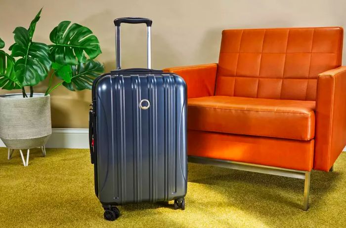 Delsey Paris Helium Aero 2-piece Luggage Set displayed near a brown leather chair