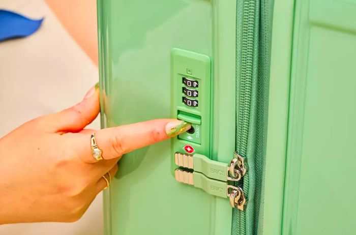 An individual indicates the lock on the Positano Expandable 27-inch Spinner