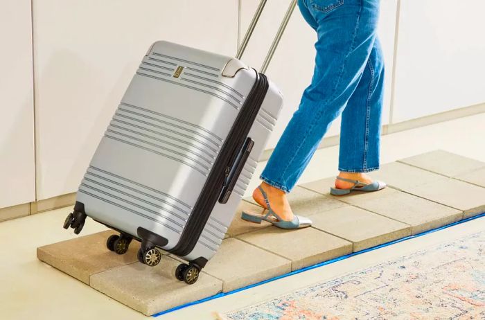 A person maneuvering the Travelpro Roundtrip Carry-On / Medium Check-In Hardside Set across tiled flooring