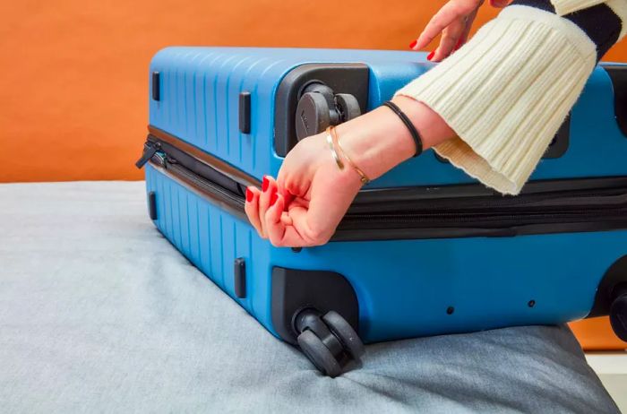 A hand closing a compartment on the Away Luggage Set