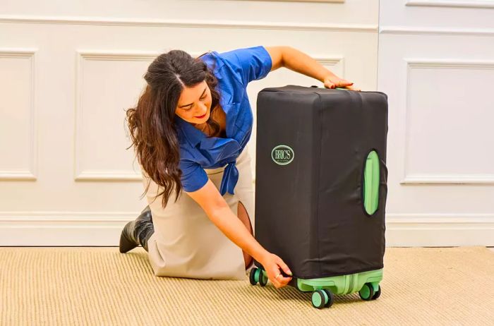 A person applies a cover to the Positano Expandable 27-inch Spinner