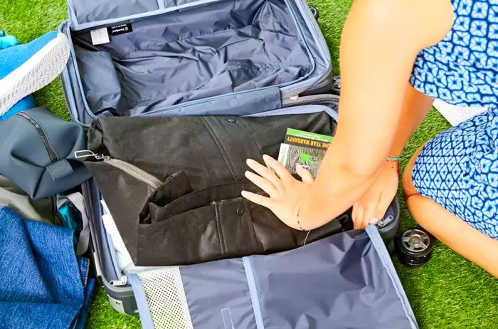 Person loading items into the Travelpro Platinum Elite Carry-on Expandable Hardside Spinner