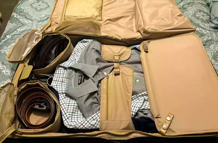 A fully packed Briggs & Riley Baseline 21-inch Carry-on Wheeled Garment Spinner resting on a bed