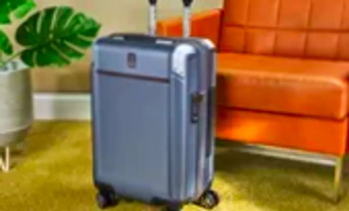 The Travelpro Platinum Elite Carry-on Expandable Hardside Spinner showcased beside a leather chair