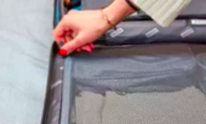 A hand zipping up an inner pocket of the Away Luggage Set